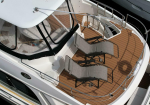 A luxury yacht aft deck with two curved fabric lounge chairs on teak flooring and stainless steel railings viewed from above.