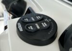 Close-up of a circular boat control with Bow Up, Bow Down, Port, and Starboard buttons on a white deck edge.