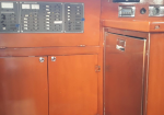 Wood-toned cabinetry with three control panels on top and a silver mini-fridge door on the right.