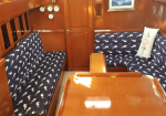 Cozy wooden boat cabin with navy seahorse-patterned upholstery on benches, a glossy wooden table, and a door at the back.