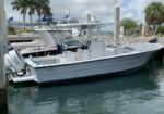 White center-console motorboat named Big Perm docked at a marina, with a Suzuki outboard and deck rigging visible nearby.