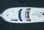 Top-down aerial view of a white luxury yacht on dark blue water, showing deck, windows, and railings from above.