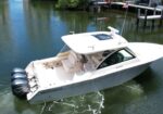 White motorboat docked on calm water, Yamaha outboard engines at stern, with a dock and American flag in the background