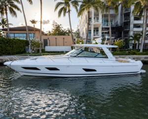 1_2855819_ | Boat Universe White luxury motor yacht docked on calm water with palm trees and apartment buildings in the background, sun glow behind the trees