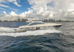 White luxury motor yacht cruising on blue water with a city skyline in the distance