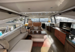 Luxurious yacht salon with beige sofas, a central coffee table, and a flat-screen TV overlooking the marina.