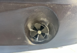 Close-up of a four-blade boat propeller inside a circular recess on a dark hull (jet drive intake).