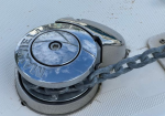 Close-up of a polished chrome boat mooring cleat with a thick chain wrapped around it on a white deck