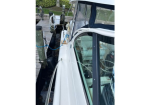 Close-up view of a white motorboat moored at a dock, showing lines, fenders, and clear cabin windows with a blue canopy.