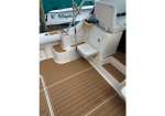 Boat cockpit with light seating, steps, and a teak-style non-slip deck; boat name 'I Utopia' visible in background.