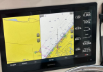 Garmin marine chartplotter screen showing nautical chart, depths, and GPS data (speed, time, position) on a boat navigation panel.