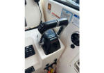 Boat helm throttle lever on a white console with a black grip and chrome trim, nearby control panel and gauges visible