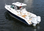 White and navy motorboat with twin outboard engines on calm water, viewed from above.