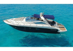 A white luxury motor yacht seen from above on bright turquoise sea, with a blue canopy and open deck Area at the stern.