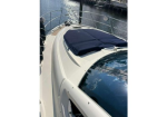 Close-up of the bow of a white motorboat with a dark blue canvas cover, moored in a marina.
