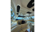 Cream-colored boat interior with curved bench seating, sunroof open to the sky, and large windows.