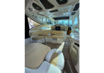 Luxurious cream and tan boat cabin interior with curved seating, a small table, and a galley counter on the right.