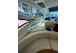 Cream leather curved seating inside a luxury yacht cabin, with large windows, helm and navigation controls visible nearby.
