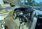 Luxury car cockpit with tan interior, steering wheel, and cluster of gauges visible through the windshield.