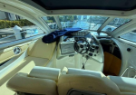 Interior of a white boat cockpit with beige seats, steering wheel, and Garmin nav display visible near the helm.