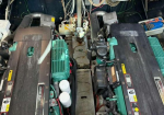 Two large diesel engines side by side in a cramped machinery space, with wiring, hoses, and control panels around them.