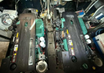 Two large diesel engines mounted side by side in a mechanical compartment, viewed from above with wiring and hoses surrounding them.