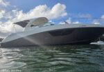Motor yacht viewed from the water, white boat with a curved windshield under a blue sky with clouds.