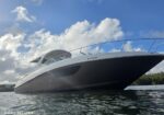 Low-angle view of a white luxury motor yacht on calm water under a blue, cloudy sky