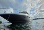 Large luxury motor yacht anchored on calm water, bow prominent with railing, blue sky and clouds above.