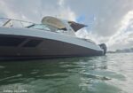 Low-angle side view of a white motor yacht on calm water with a cockpit canopy extended over the deck.
