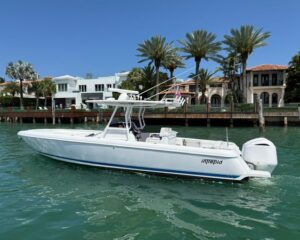 2012-intrepid-32-open-power-9817278-20250527163741566-1_XLARGE | Boat Universe White powerboat named Intrepid touring turquoise water near a waterfront with palm trees and luxury houses in the background