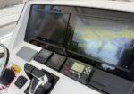 Boat helm with two large navigation screens, throttle, and marine electronics on a sunny deck.
