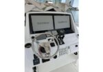 Boat helm featuring two Garmin screens, a polished stainless steering wheel, and navigation controls on a white yacht.