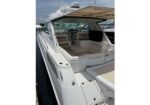 White motor yacht rear deck with open seating area and built-in storage, docked at a marina under a clear sky.