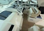 Luxury yacht cockpit with cream captain's chair, steering wheel, and navigation screens at the helm aboard a motorboat.
