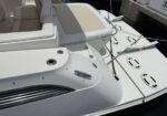 White motorboat deck with beige seating, a mooring line on a cleat, and round deck hatches.