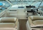 Boat cockpit with beige captain's chairs, wood deck, and helm featuring a Garmin display and steering wheel aboard a marina vessel