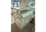 White and beige yacht captain's chair with cushioned back and armrests on a teak deck by the marina