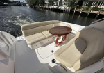Cream-colored seating area and a small round wooden table aboard a white boat on a canal.