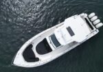 Top-down view of a white motor yacht with multiple engines at the stern on dark water