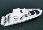 White motor yacht viewed from above on dark water, with a solar panel on the cabin roof and four outboard engines at the stern.