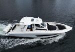 White motorboat cruising on dark water, with a cabin and twin stern engines visible at the back.