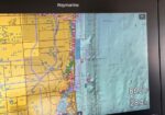 Raymarine chartplotter screen showing a coastal map: yellow landmass on the left, blue-green water on the right, with navigation markers along the shoreline and depth readout 28.4 ft and water temperature 86.0 °F.