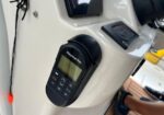 Raymarine marine navigation display mounted on a white boat console, with a button keypad below the screen.