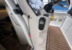 Inside a boat cockpit entry showing a mounted Raymarine marine handheld display on a white console beside a teak deck and cabin doorway