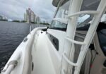 White yacht deck with railing on a calm river and city high-rises in the distance