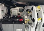 Industrial electrical cabinet area showing a battery bank, inverter/charger modules, and assorted wiring within a compact machinery enclosure.