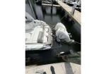 White speedboat docked at a marina, tied to a wooden pier with calm water around it.