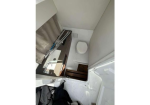 Tiny bathroom in a compact mobile space: toilet against the far wall, sink with faucet on the left, wooden steps nearby, and a curtain on the left side.