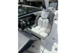 Captain's chair in a boat cockpit with light gray and white upholstery, steering wheel and controls nearby.